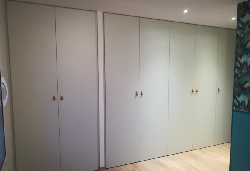 Pour une chambre à Castelnau-Tursan, agencement intérieur avec placards blancs toute hauteur aux portes fermées