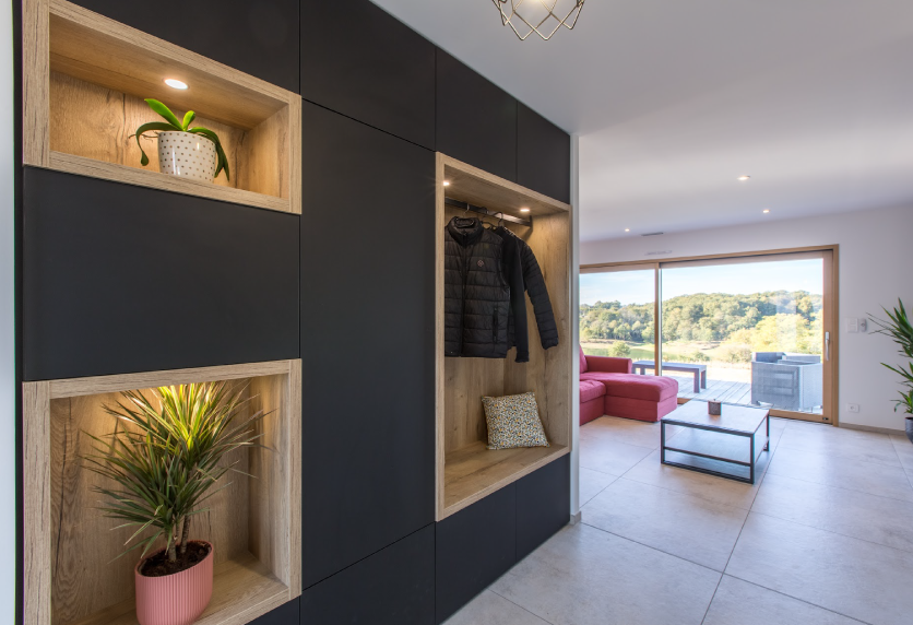 Agencement intérieur pour une maison à Hagetmau : meuble d’entrée anthracite avec niches en bois et penderie ouverte