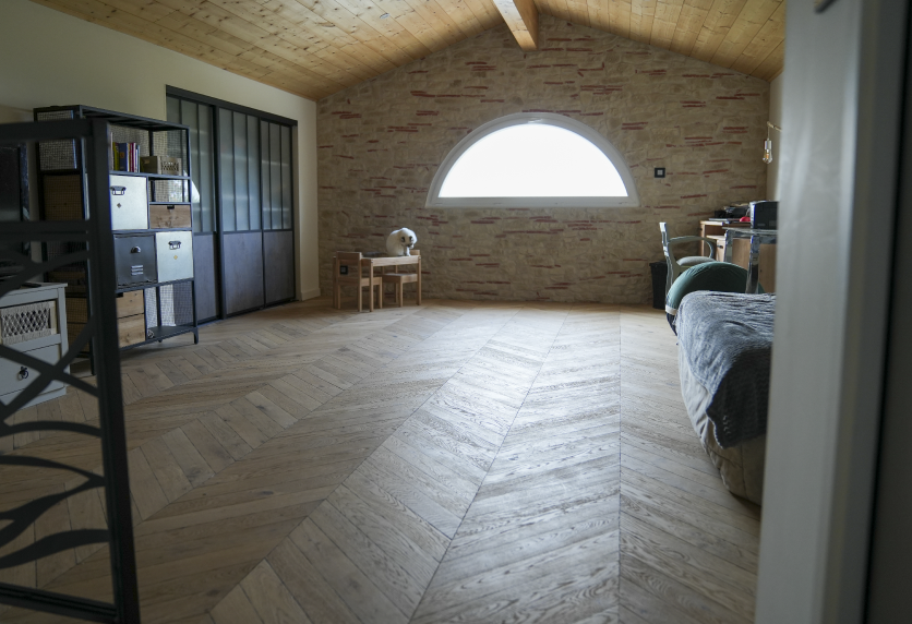 int-02.pngDans une pièce aux murs en pierre à Audignon, l’agencement intérieur associe parquet en chevrons et rangements vitrés