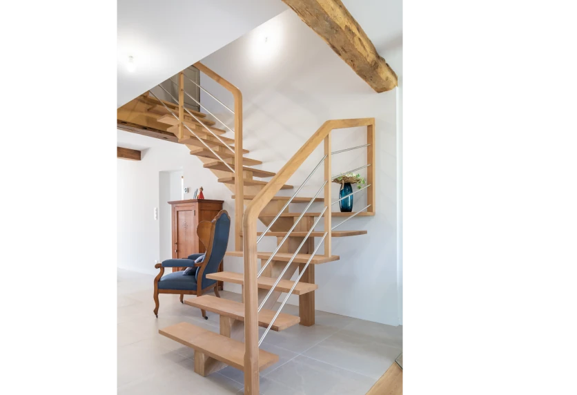 Escalier en bois à limon central sous une poutre apparente, dans un projet d’agencement intérieur à Bats