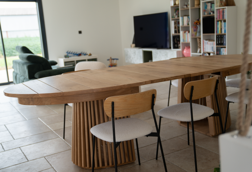 À Hagetmau, agencement intérieur d’un espace repas avec table ovale en bois et piètement à tasseaux