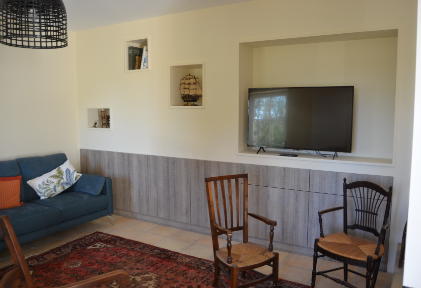 Meuble bas aspect bois et niches murales autour du téléviseur, pour un agencement intérieur à Sorbets