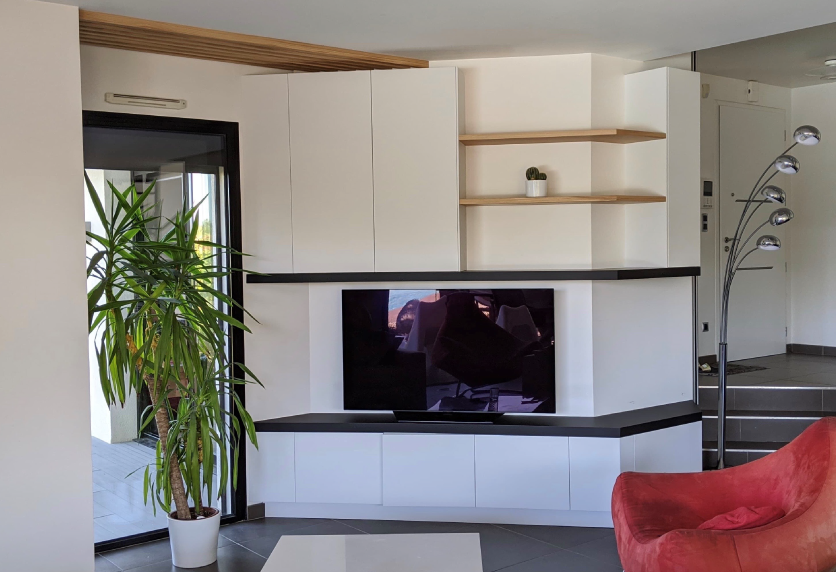 Agencement intérieur d’un salon à Garlin avec rangements blancs, étagères en bois et télévision intégrée