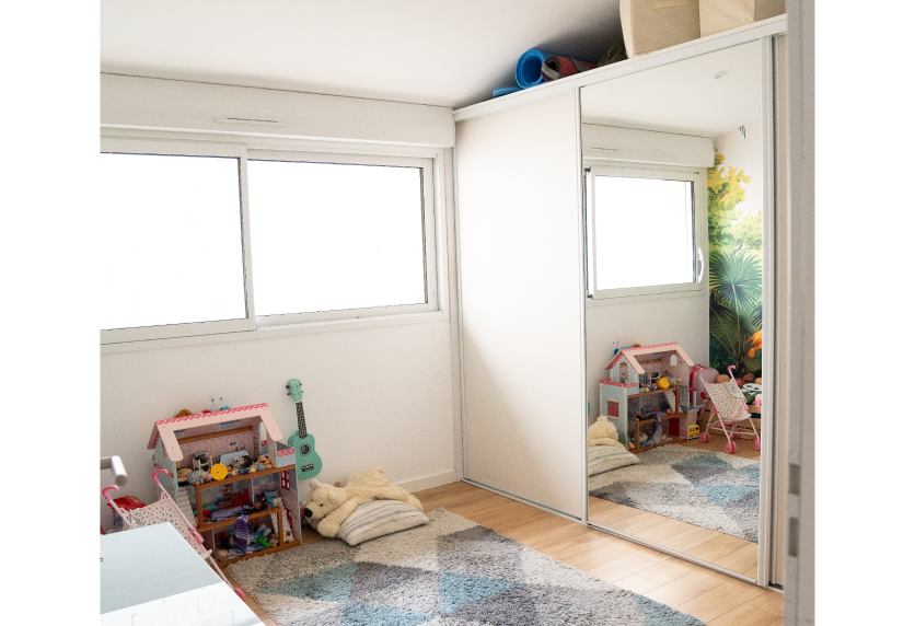 Dans une chambre d’enfant à Audignon, agencement intérieur avec placard blanc à portes coulissantes et miroir