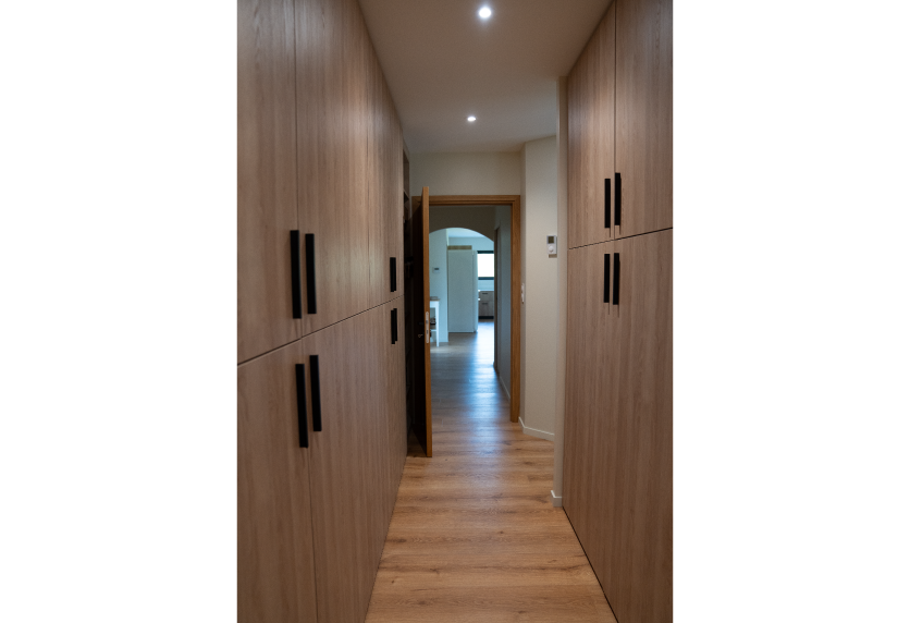 Agencement intérieur d’un couloir à Serres-Gaston, avec placards en bois clair et poignées noires de chaque côté