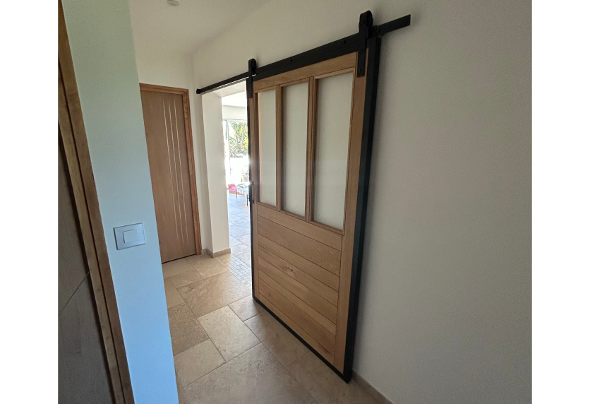 Porte coulissante en bois et verre dépoli dans un couloir à Audignon, intégrée à l’agencement intérieur
