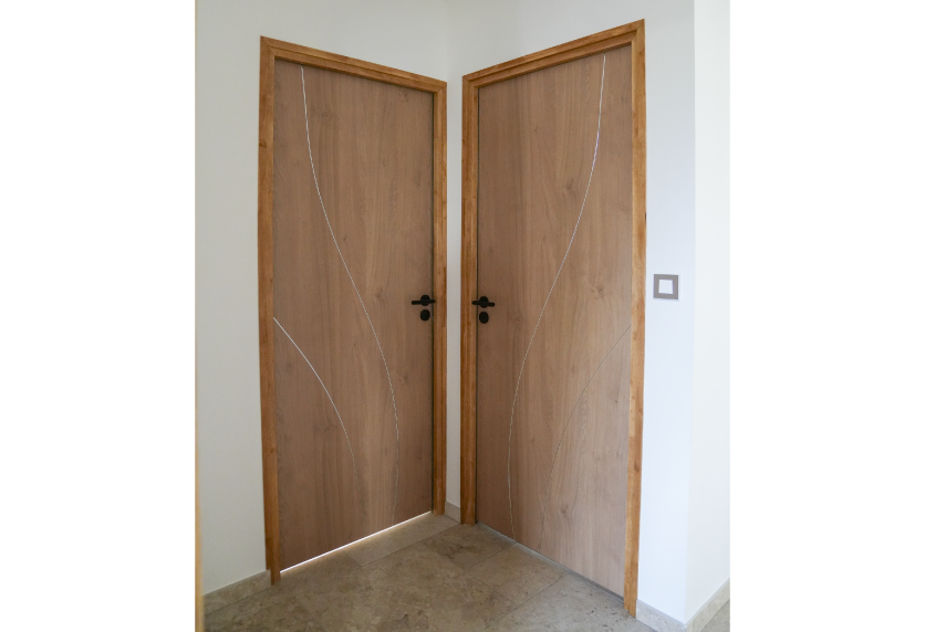 Deux portes en bois à motifs courbes réunies dans un angle, détail d’agencement intérieur pour Clèdes