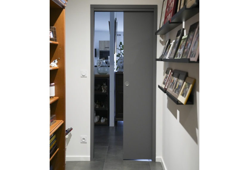 À Lauret, porte coulissante grise vitrée séparant deux pièces dans un agencement intérieur