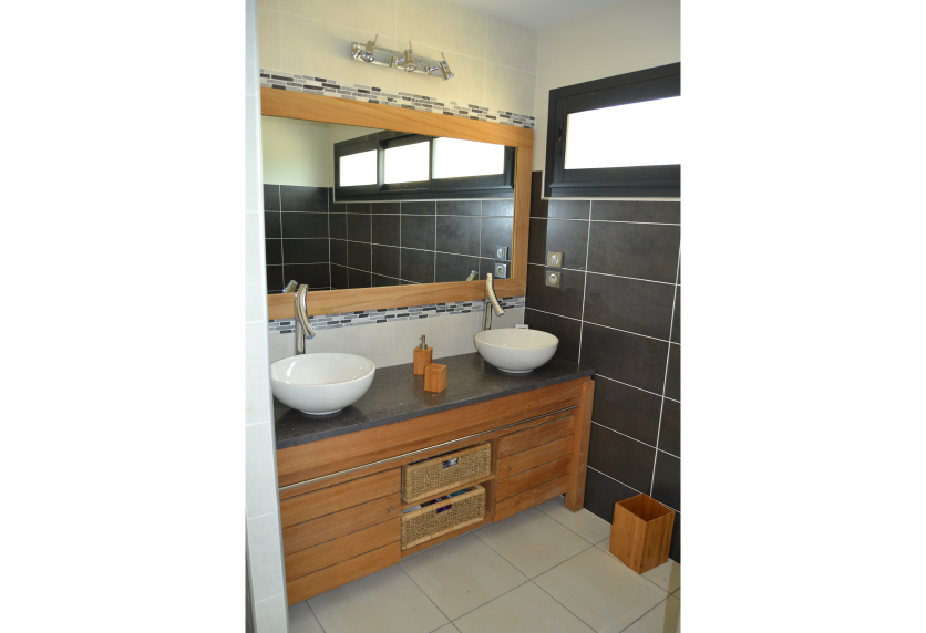 Pour une salle de bain à Samadet, agencement intérieur avec meuble en bois, deux vasques et carrelage mural noir