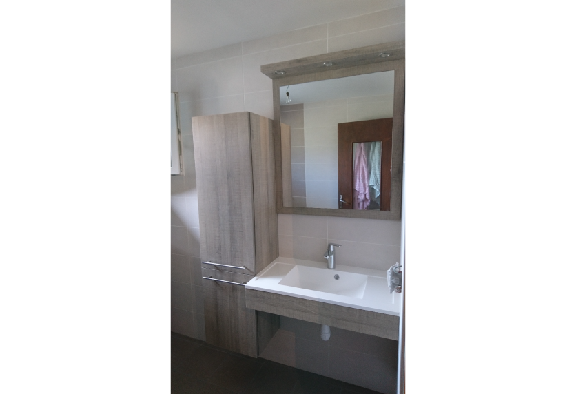 Pour un projet à Garlin, agencement intérieur associant meuble vasque blanc, colonne de rangement et miroir encadré