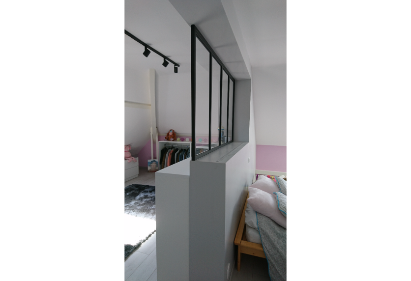 Verrière noire sur demi-cloison entre deux espaces, avec rail de porte coulissante, pour un agencement intérieur à Clèdes.