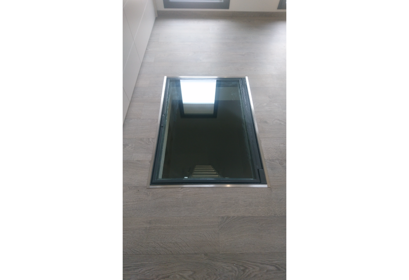 Vue rapprochée d’un plancher vitré laissant voir l’escalier, détail d’agencement intérieur pour une maison à Lauret.