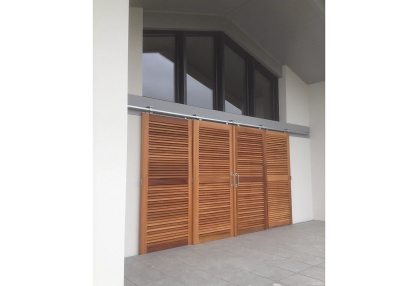 Pour une maison à Pau, portes à persiennes en bois sous une grande fenêtre vitrée, réalisées par Menuiserie Joie