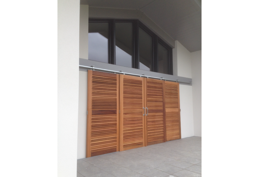 Pour une maison à Pau, portes à persiennes en bois sous une grande fenêtre vitrée, réalisées par Menuiserie Joie