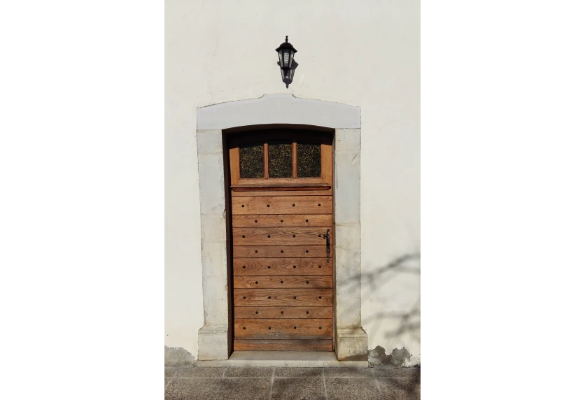 Menuiserie en bois pour une habitation à Lons : petite porte à lames horizontales sur une façade blanche