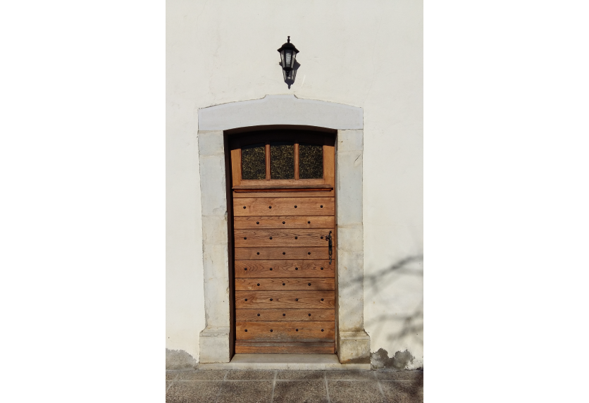 Menuiserie en bois pour une habitation à Lons : petite porte à lames horizontales sur une façade blanche