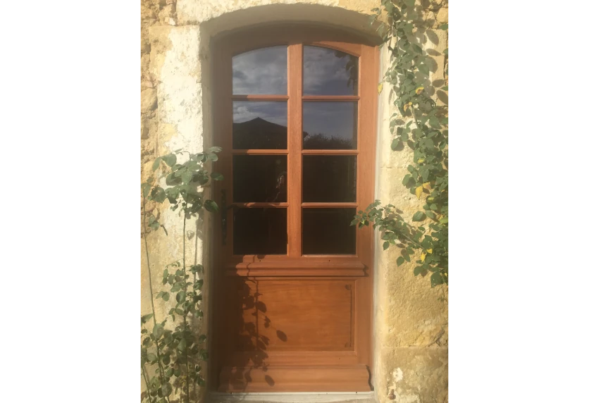 Sous une arche en pierre à Lescar, porte de menuiserie en bois vitrée à quatre carreaux