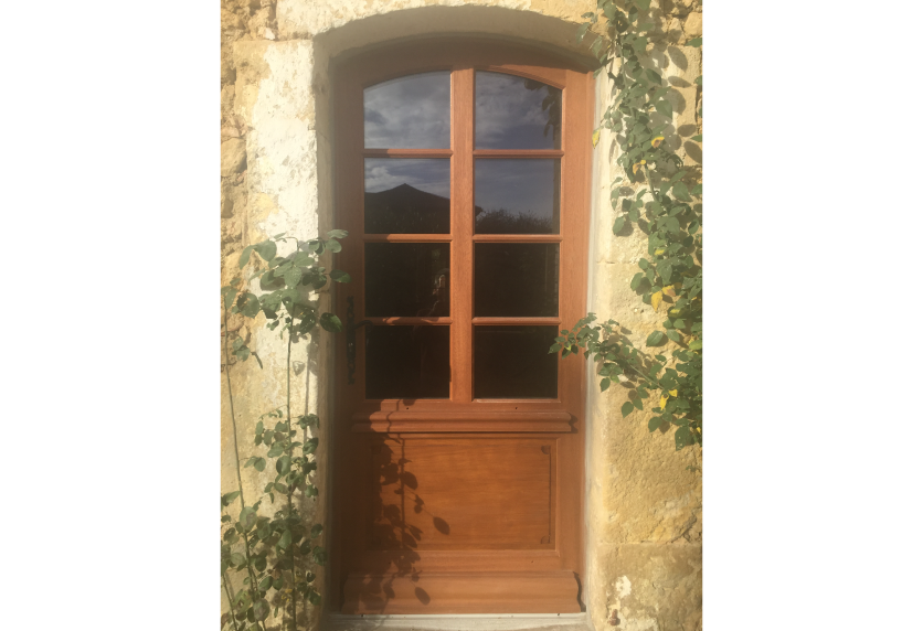 Sous une arche en pierre à Lescar, porte de menuiserie en bois vitrée à quatre carreaux