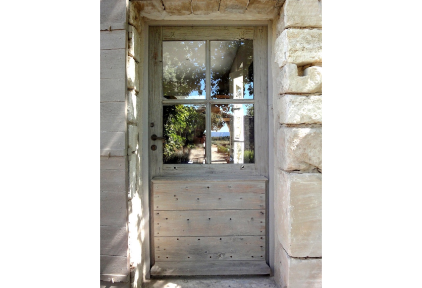 À Montardon, une porte ancienne en bois clair avec vitrage supérieur illustre la menuiserie traditionnelle