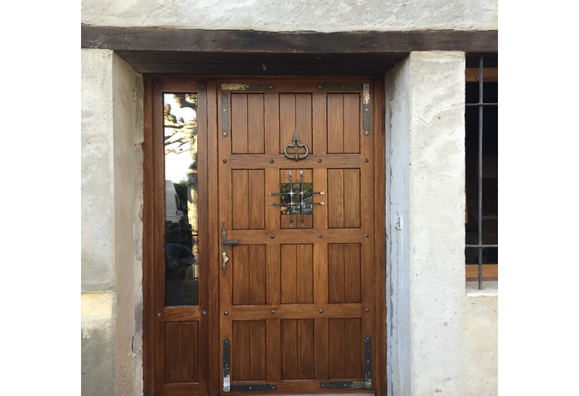 Porte d’entrée en menuiserie bois avec panneaux et vitrages latéraux pour une maison à Navailles-Angos