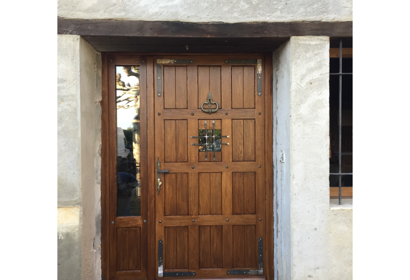 Porte d’entrée en menuiserie bois avec panneaux et vitrages latéraux pour une maison à Navailles-Angos