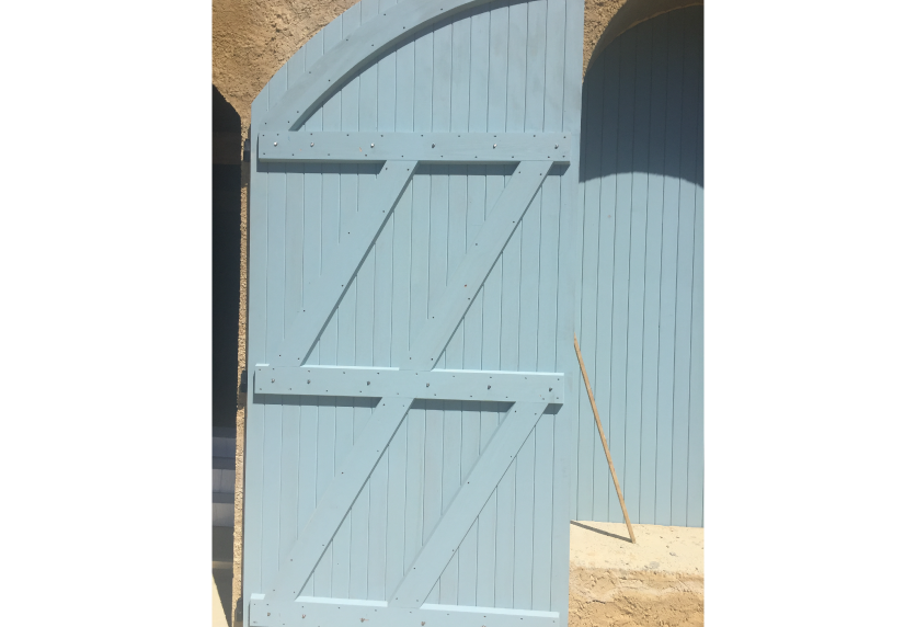 Volet bleu clair à sommet cintré et ferrures apparentes : une menuiserie en bois pour une façade à Miossens-Lanusse