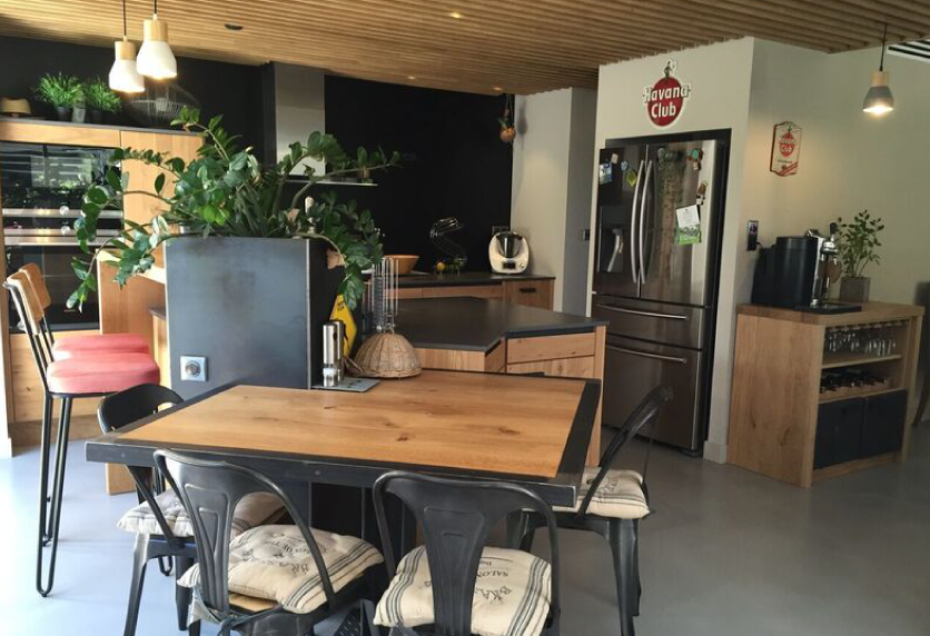 Cuisine ouverte près de Castelnau-Tursan, associant une table en bois, des chaises noires et des rangements sombres