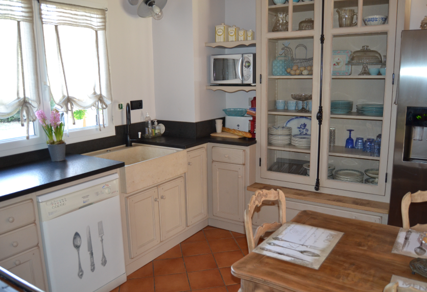Cuisine de style traditionnel à Lauret, avec meubles blancs, vitrines et plan de travail sombre