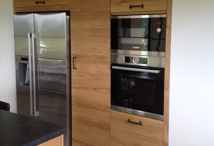 Colonne de cuisine en bois intégrant un four, à côté d’un réfrigérateur en inox, pour une maison à Bats