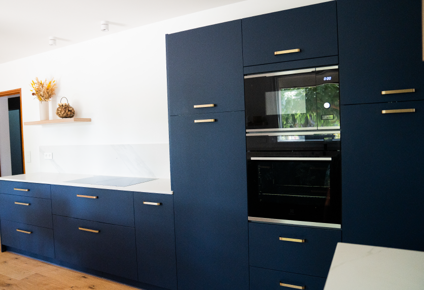 Pour un projet à Castelnau-Tursan, cuisine bleu foncé avec four intégré et poignées dorées