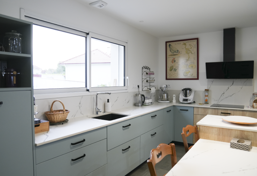 Sous les fenêtres d’une maison à Pécorade, cuisine gris clair avec évier noir et rangements à tiroirs