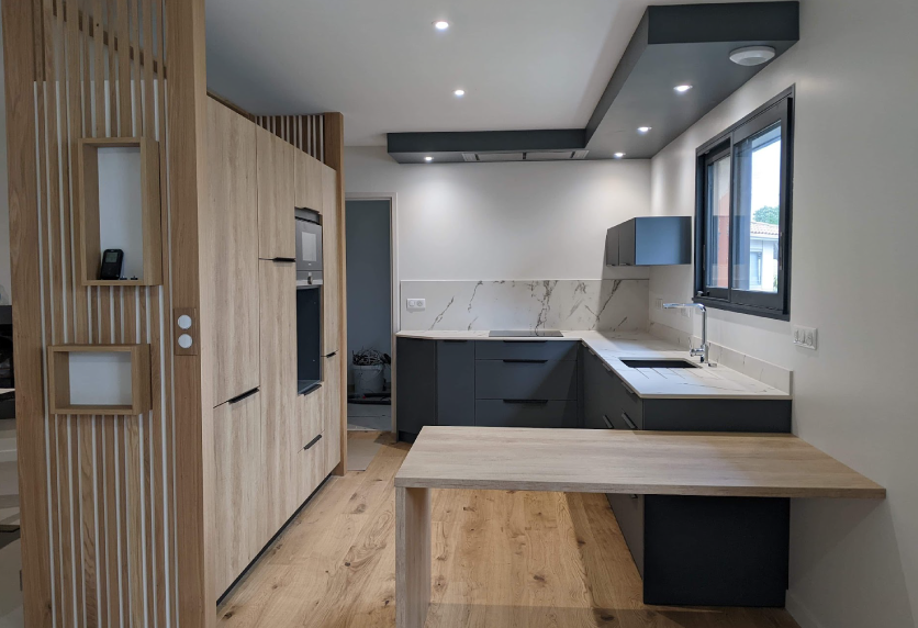 Pour une cuisine à Garlin, meubles aspect bois, façades gris foncé et table intégrée au plan de travail