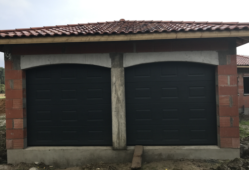 Deux portes de garage foncées côte à côte sur une construction en briques, pour une maison à Garlin.