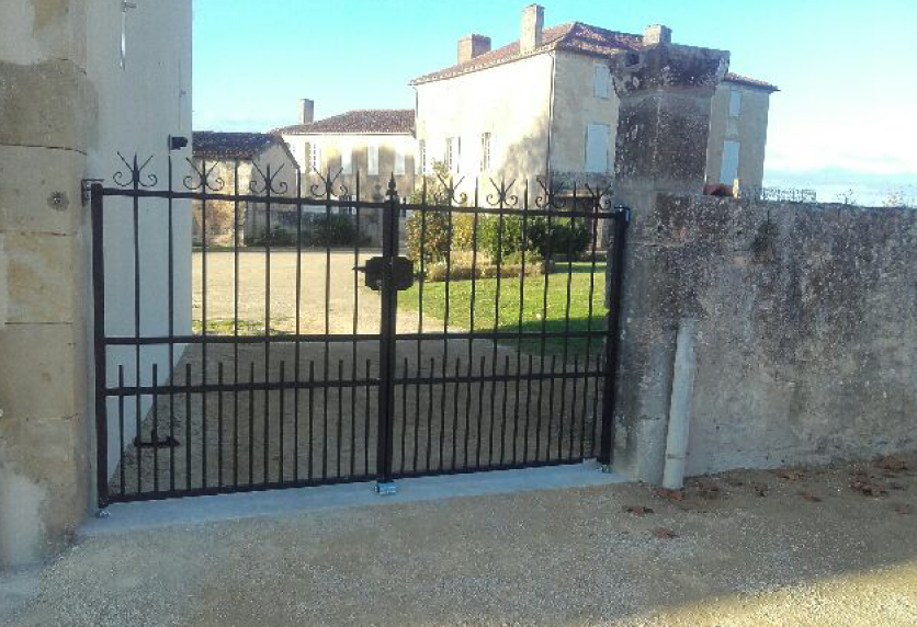 Portail noir ajouré devant une cour, exemple de menuiserie extérieure pour une propriété à Montardon