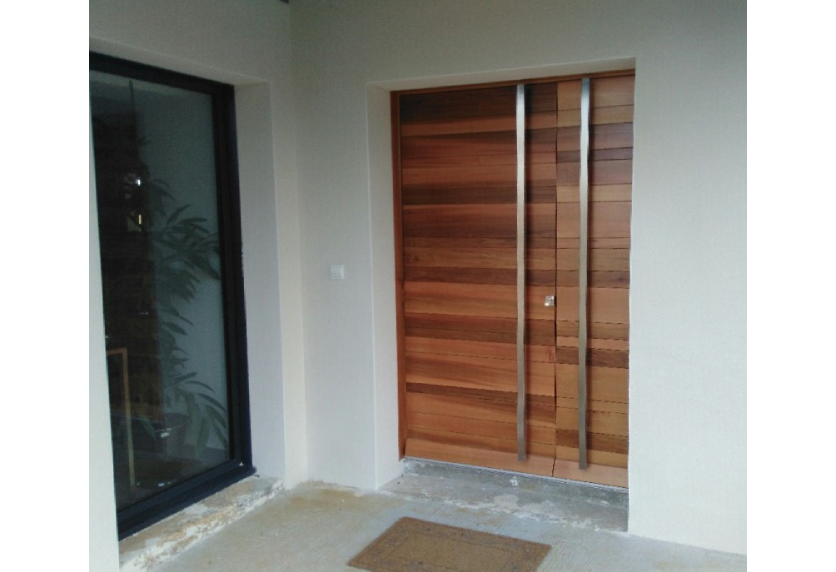 Pour une entrée à Lons, menuiserie à double porte aspect bois avec lames horizontales et longues poignées verticales