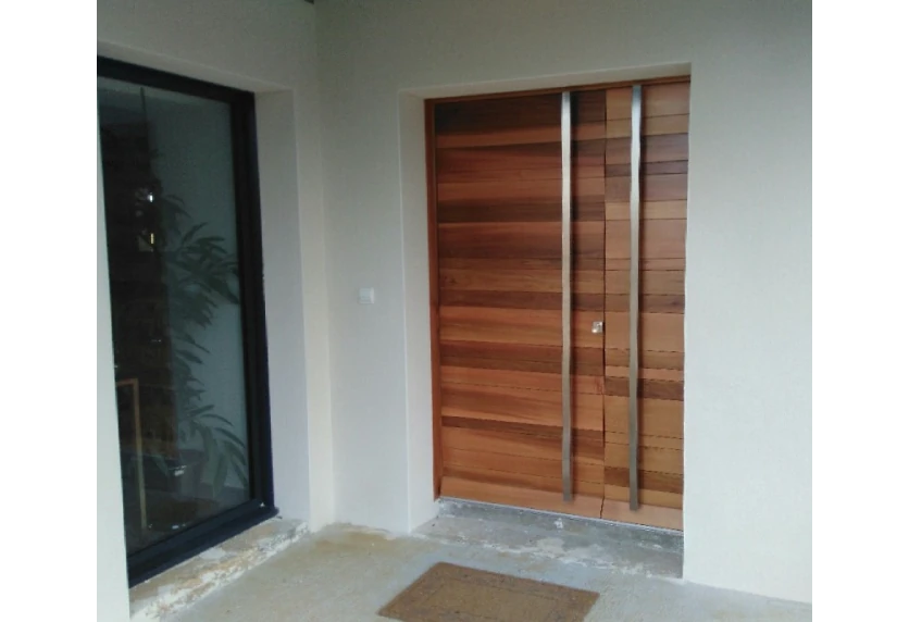 Pour une entrée à Lons, menuiserie à double porte aspect bois avec lames horizontales et longues poignées verticales