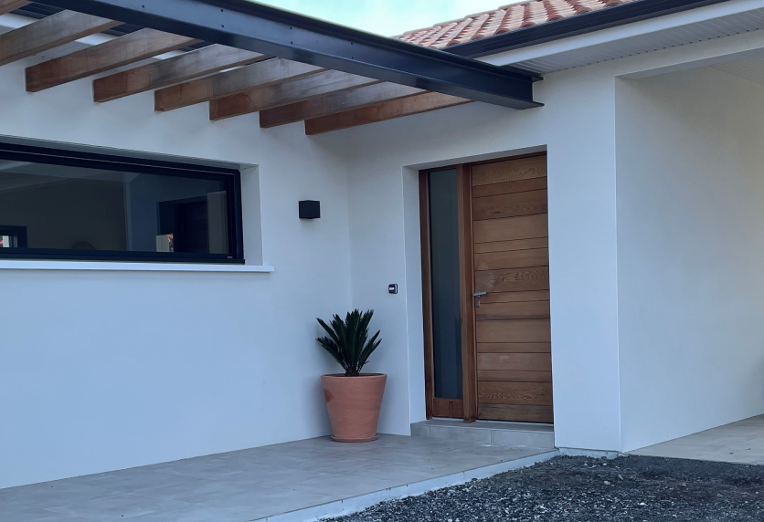 Pour une entrée à Lons, menuiserie à double porte aspect bois avec lames horizontales et longues poignées verticales