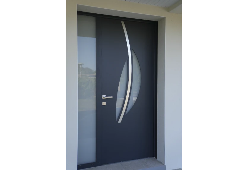 Porte d’entrée anthracite à vitrage courbe et poignée discrète, proposée en menuiserie pour une maison à Garlin
