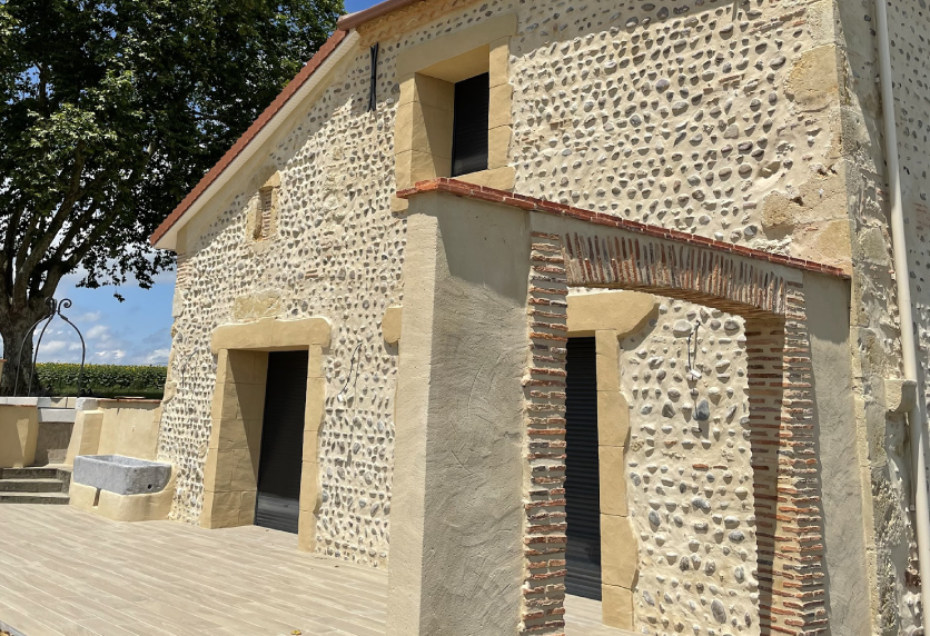 Sur une maison en pierre à Navailles-Angos, la menuiserie accompagne les ouvertures de la façade rénovée