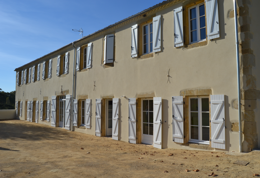 À Garlin, les fenêtres et portes vitrées de cette longue façade composent un ensemble de menuiserie aux volets clairs